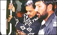 Javed Iqbal (left) in black being led into court to hear the verdict (Dawn)